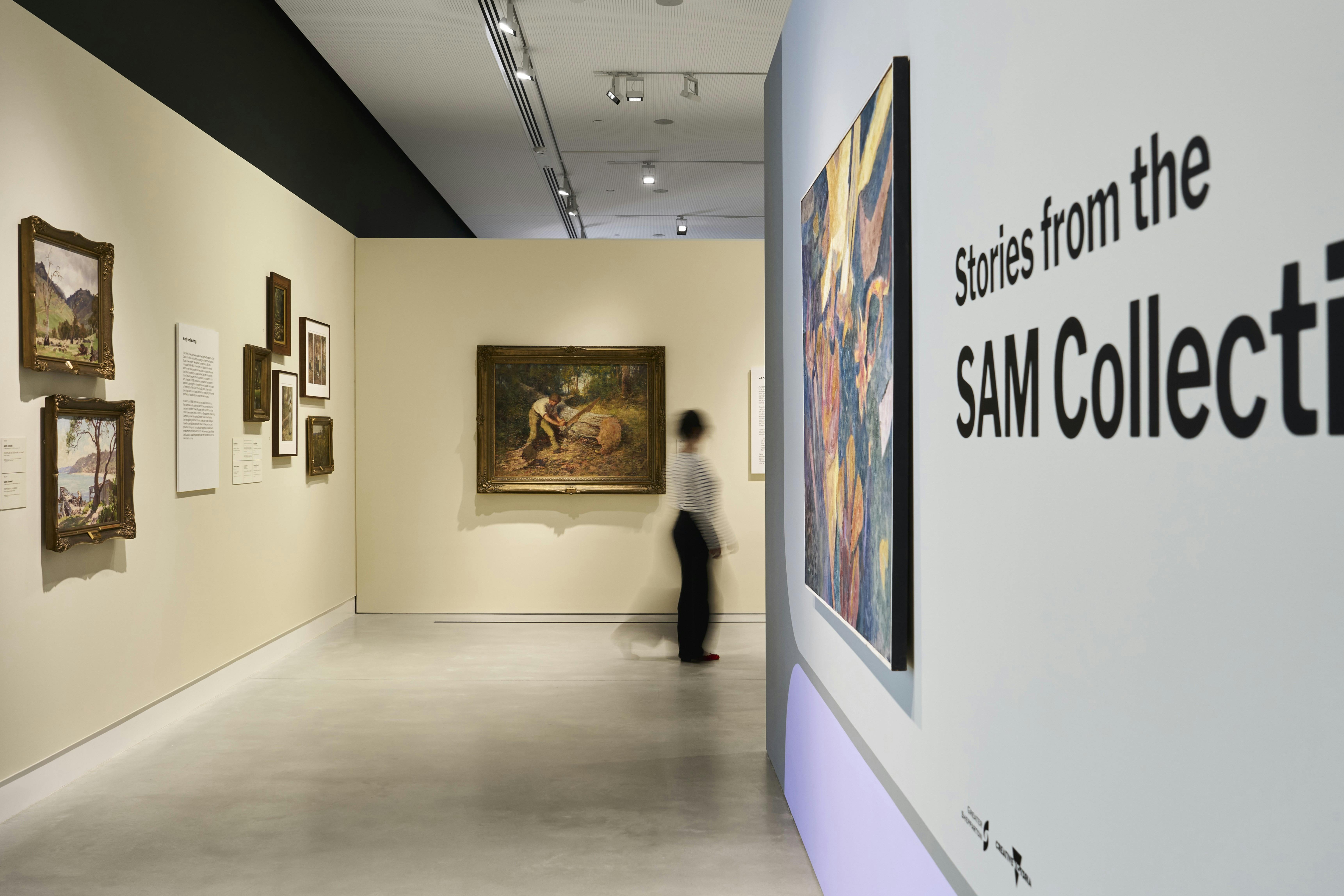 A woman walks past colonial-era paintings in an art gallery