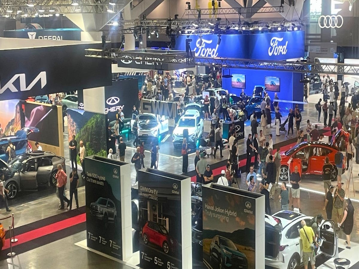 Crowds explore electric and hybrid cars from top brands at a busy auto show.