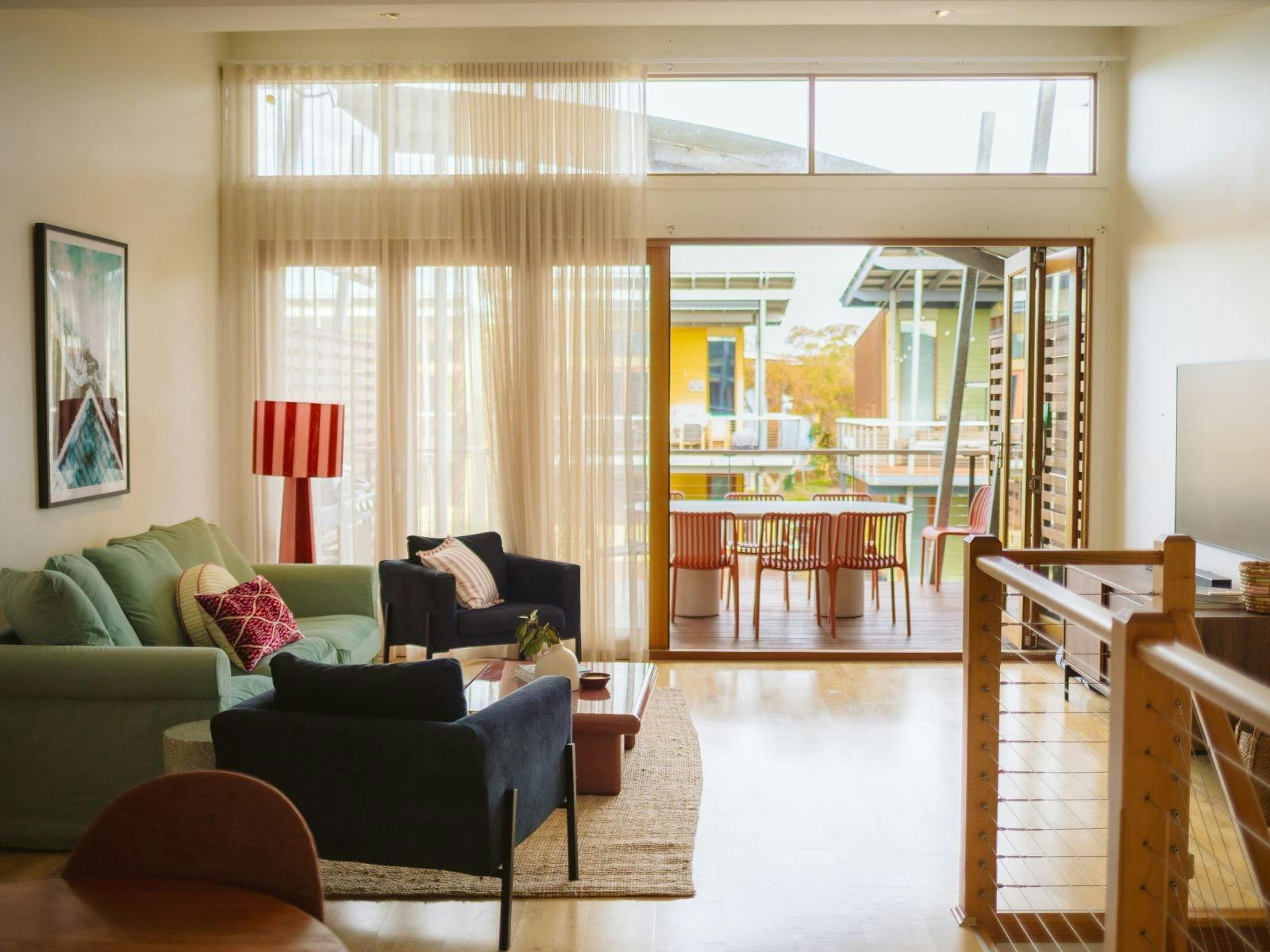 Light-filled living room with comfy sofas, playful styling and doors opening to the deck