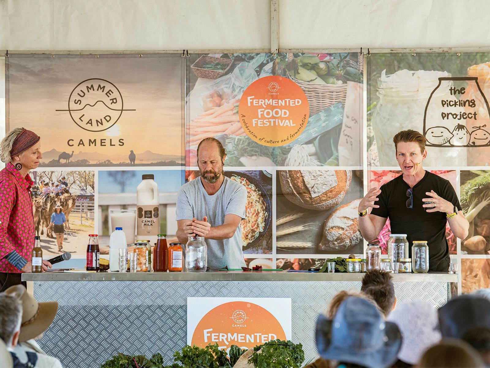 Guest speakers standing at a bench talking and giving a live demonstration on fermenting practices.
