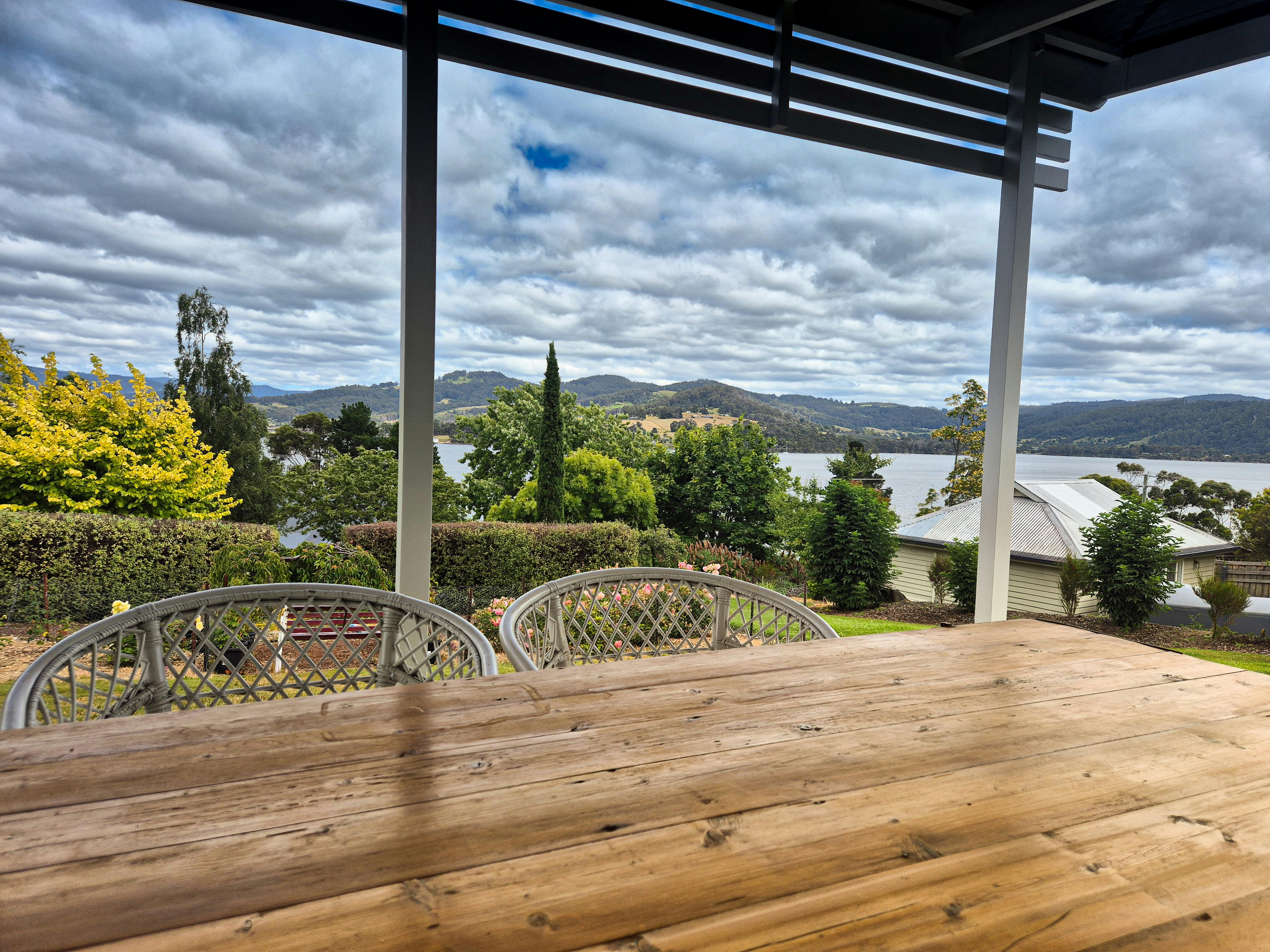 Outdoor dining area at Florian Cottage overlooking the Huon River and valley in Tasmania.