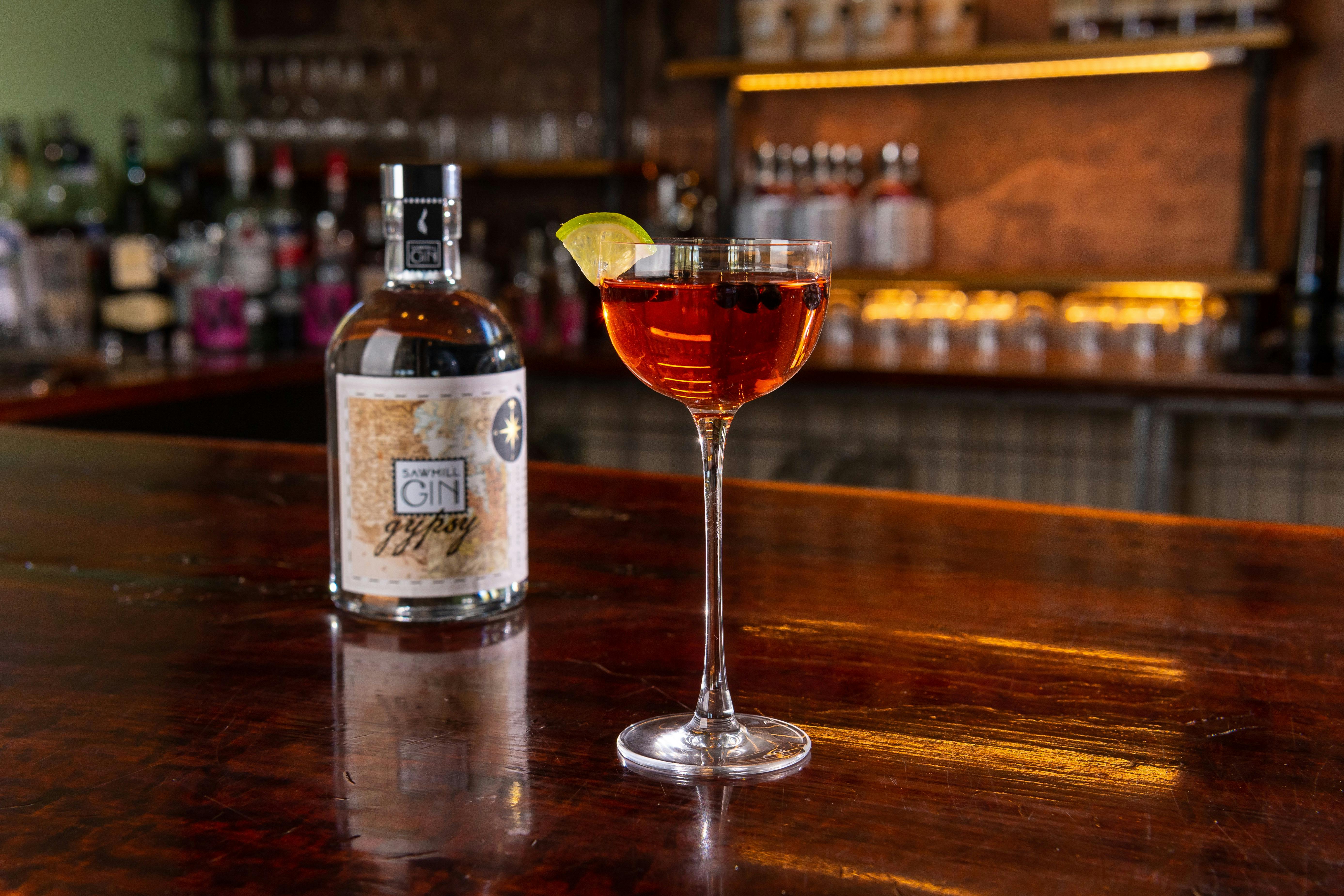 A cocktail glass with Gypsy Gin bottle in the background