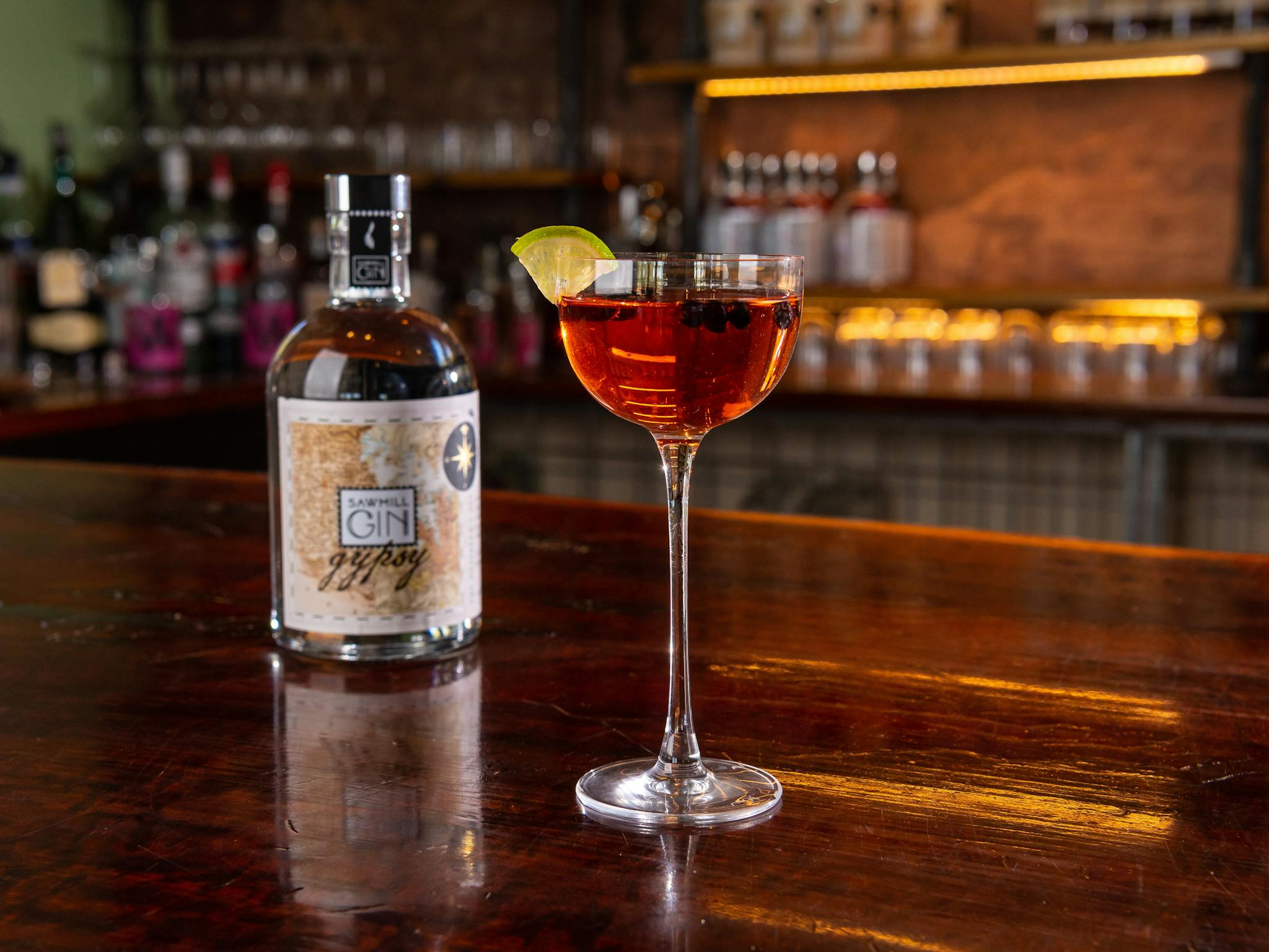 A cocktail glass with Gypsy Gin bottle in the background