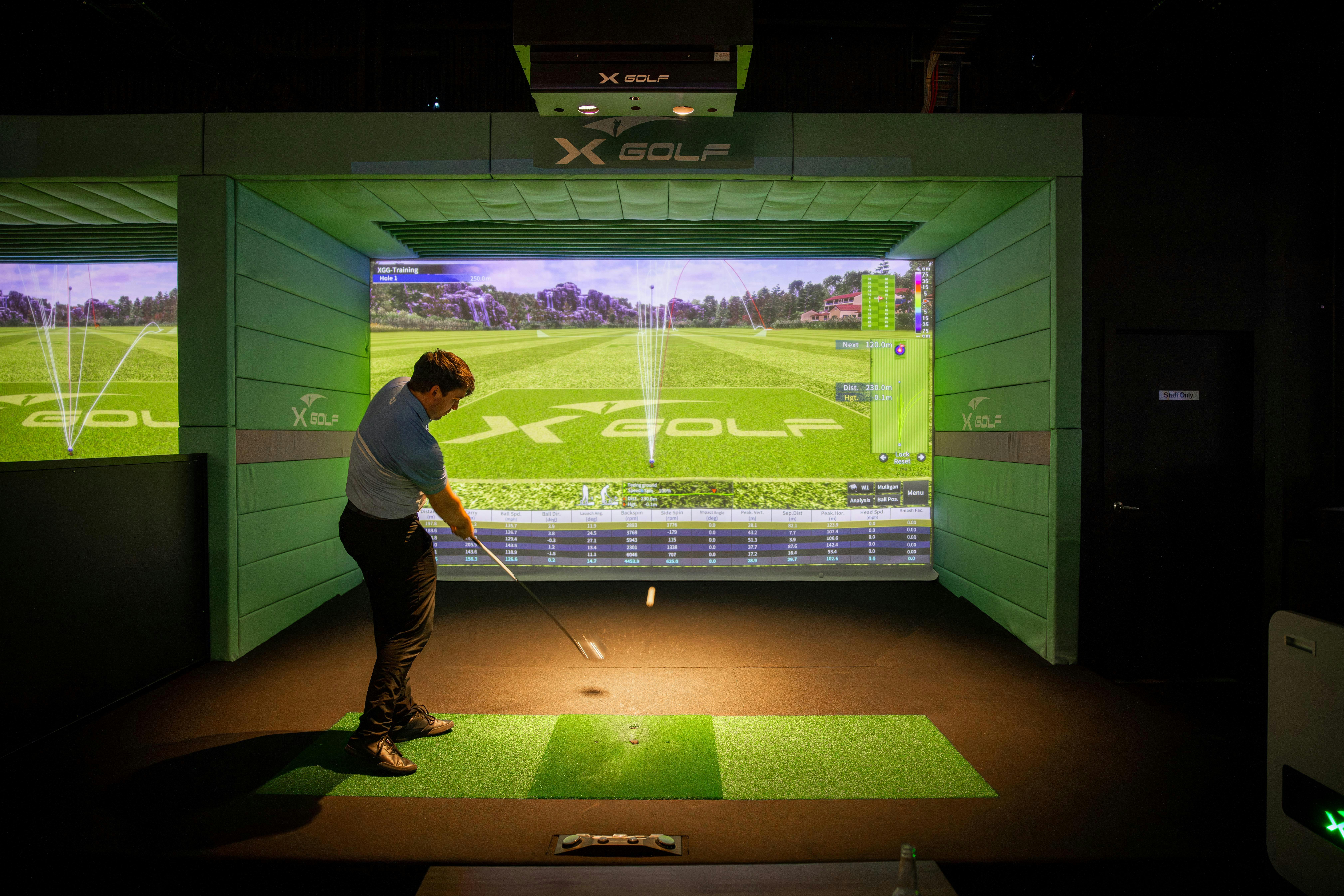 Man Swinging a Club in front of a Golf Simulator at X-Golf Launceston