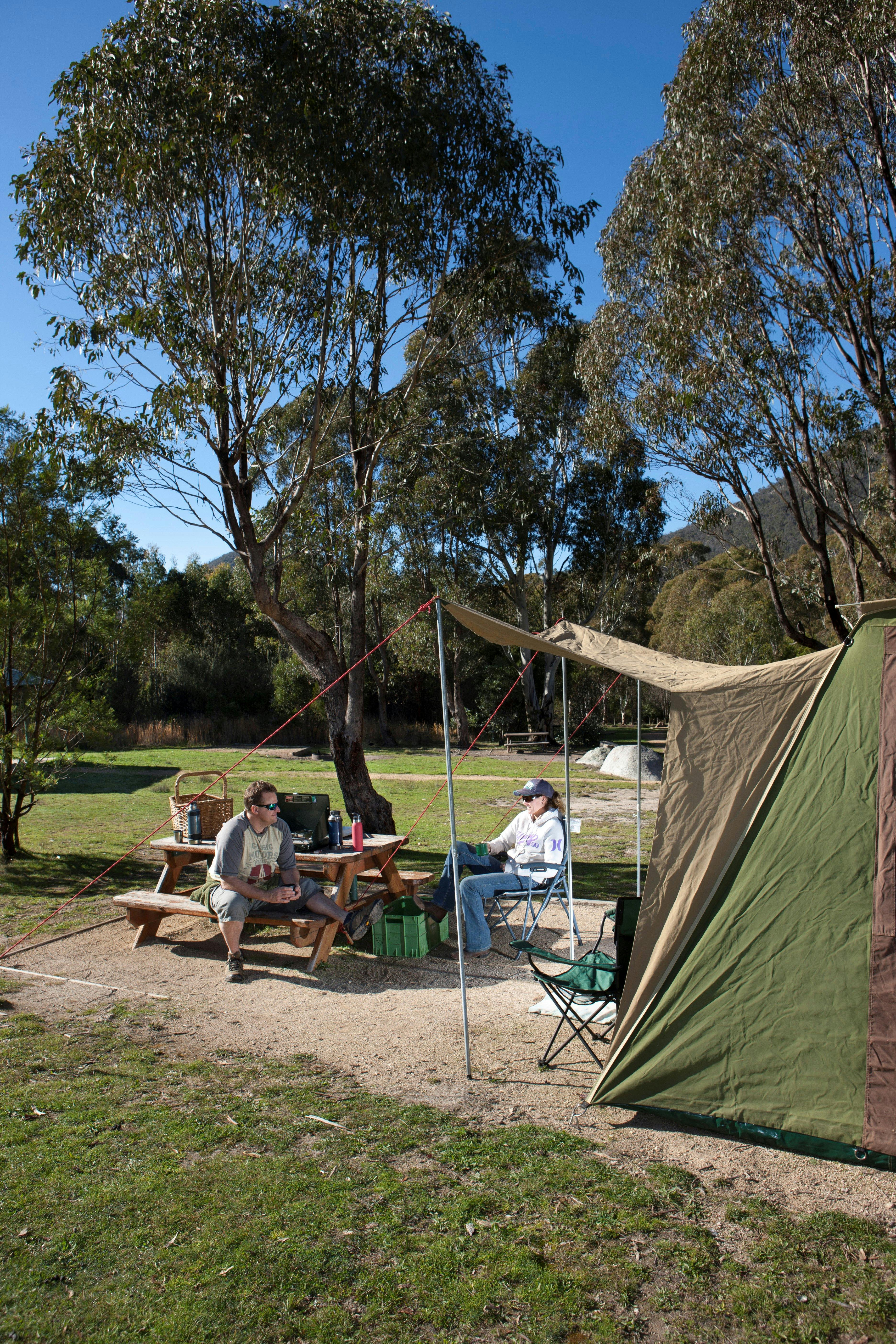 Campers sitting beside tent at Woods Reserve