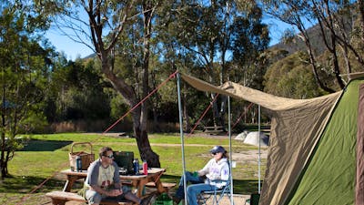 Campers sitting beside tent at Woods Reserve