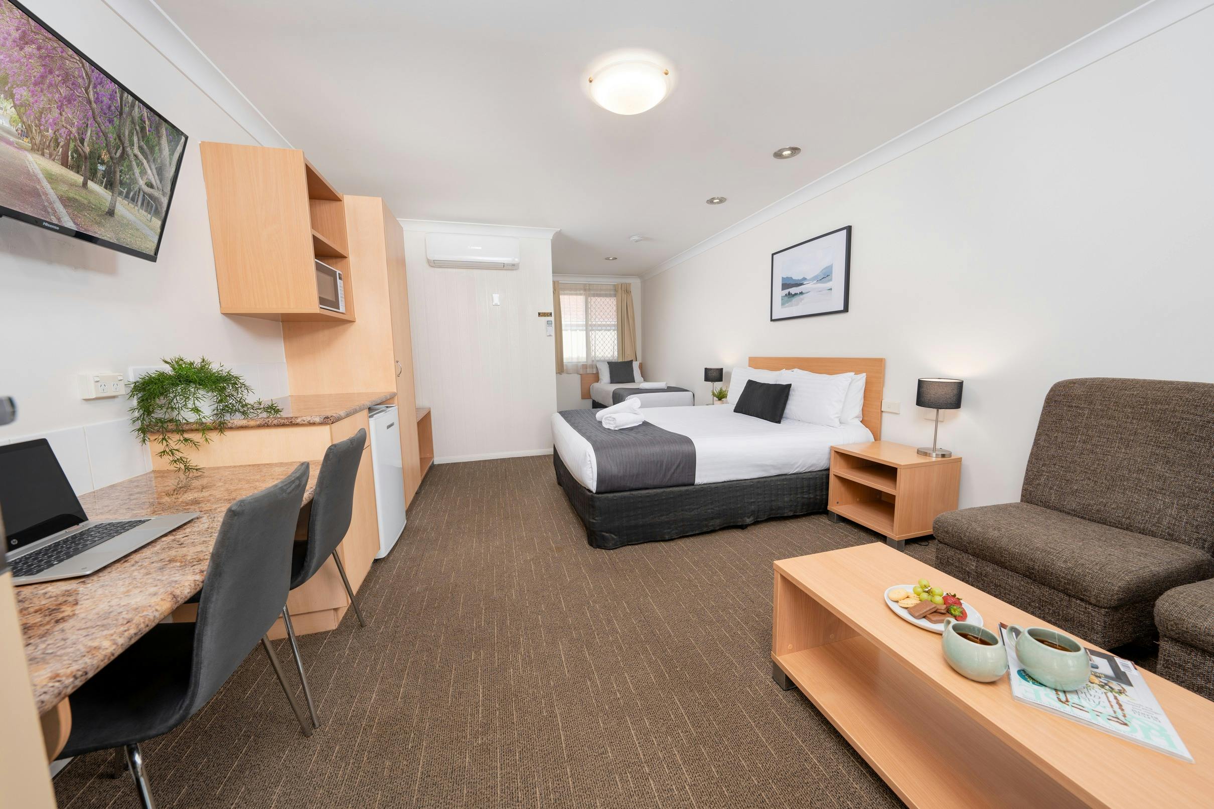 Motel Room with Queen bed, Single bed, desk space, lounge seating and coffee table.