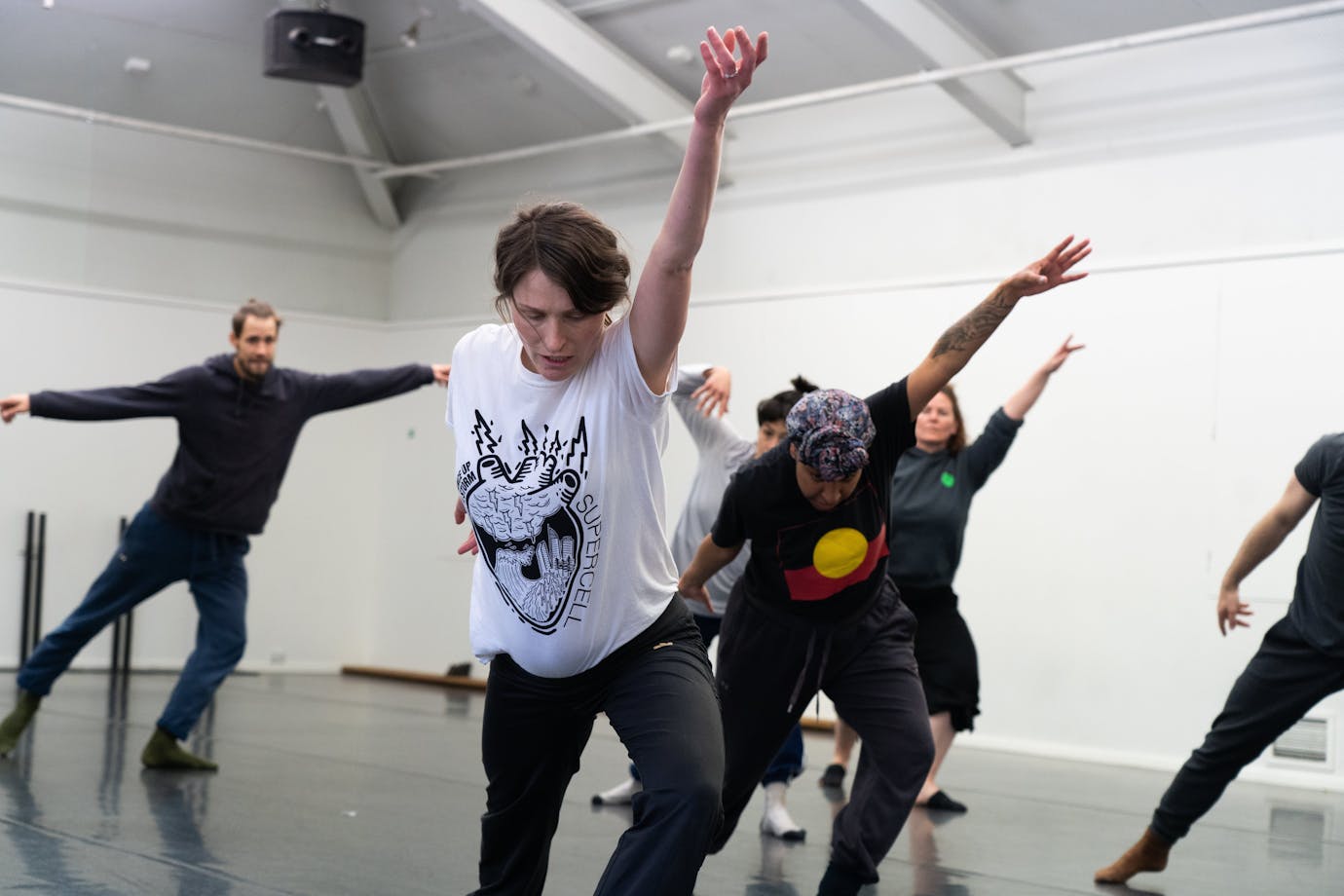 A group of people in the middle of a movement, lunging with their arm up and looking down.