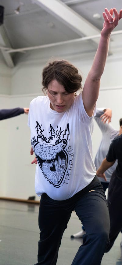 A group of people in the middle of a movement, lunging with their arm up and looking down.