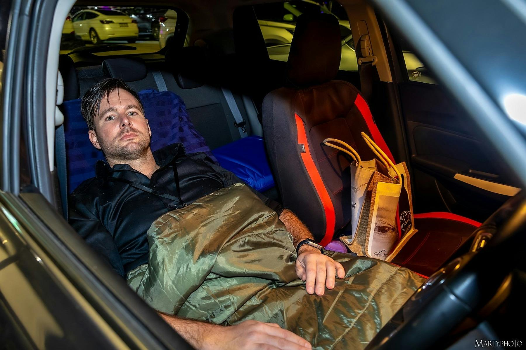 Participant lying in the back seat of a car with a sleeping bag during the Live Like Her Challenge.