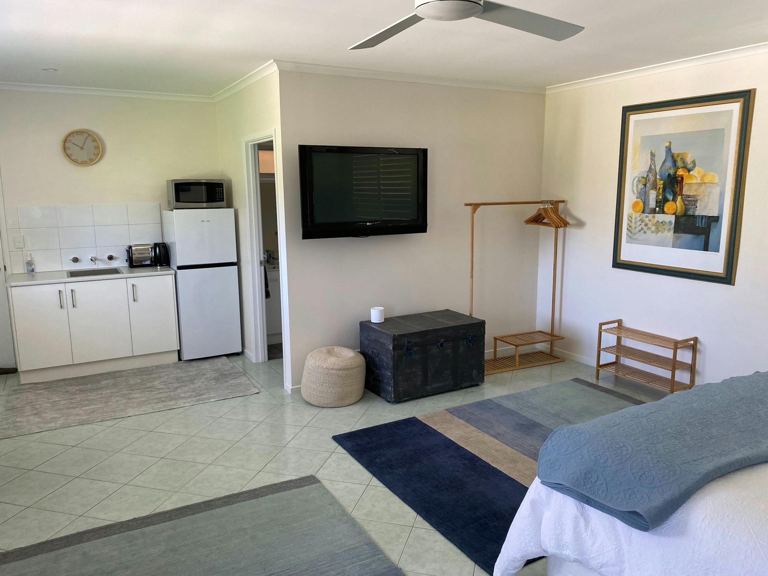 Bed looking towards kitchenette, picture on the wall and rug.