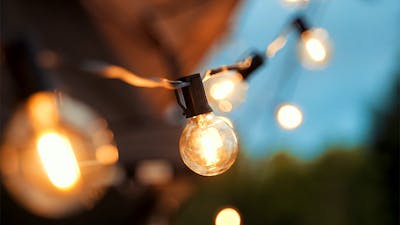 A string of feature festoon lights glow with a warm yellow against a twilight sky