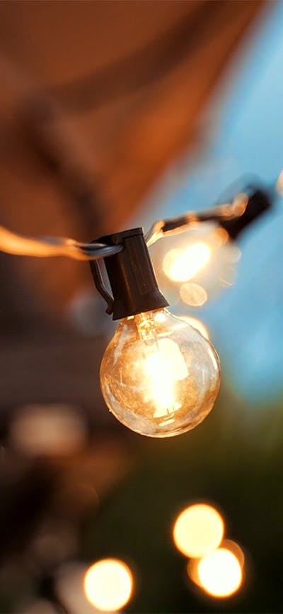 A string of feature festoon lights glow with a warm yellow against a twilight sky