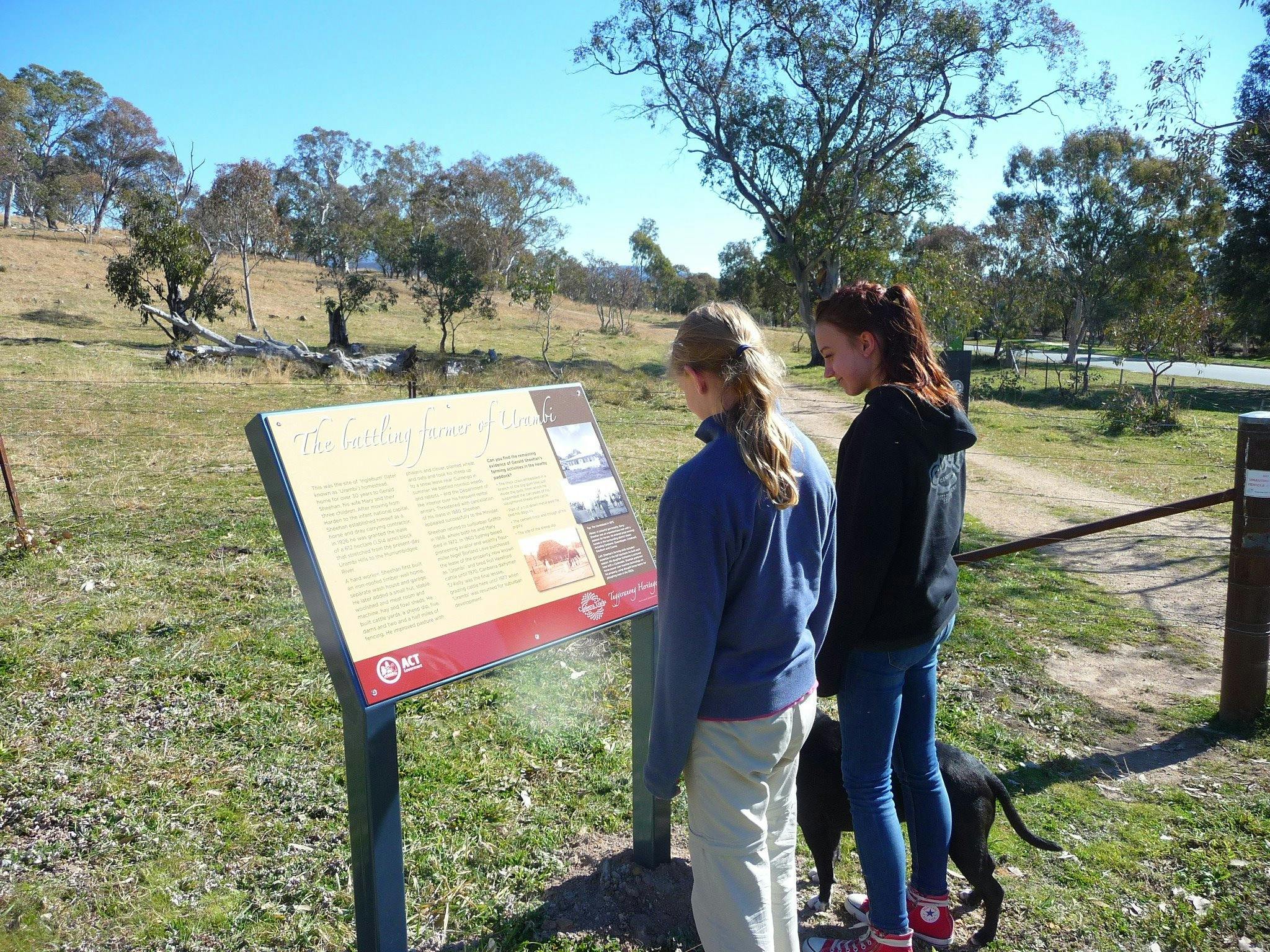 Two girls with dog at a sign board in open woodland