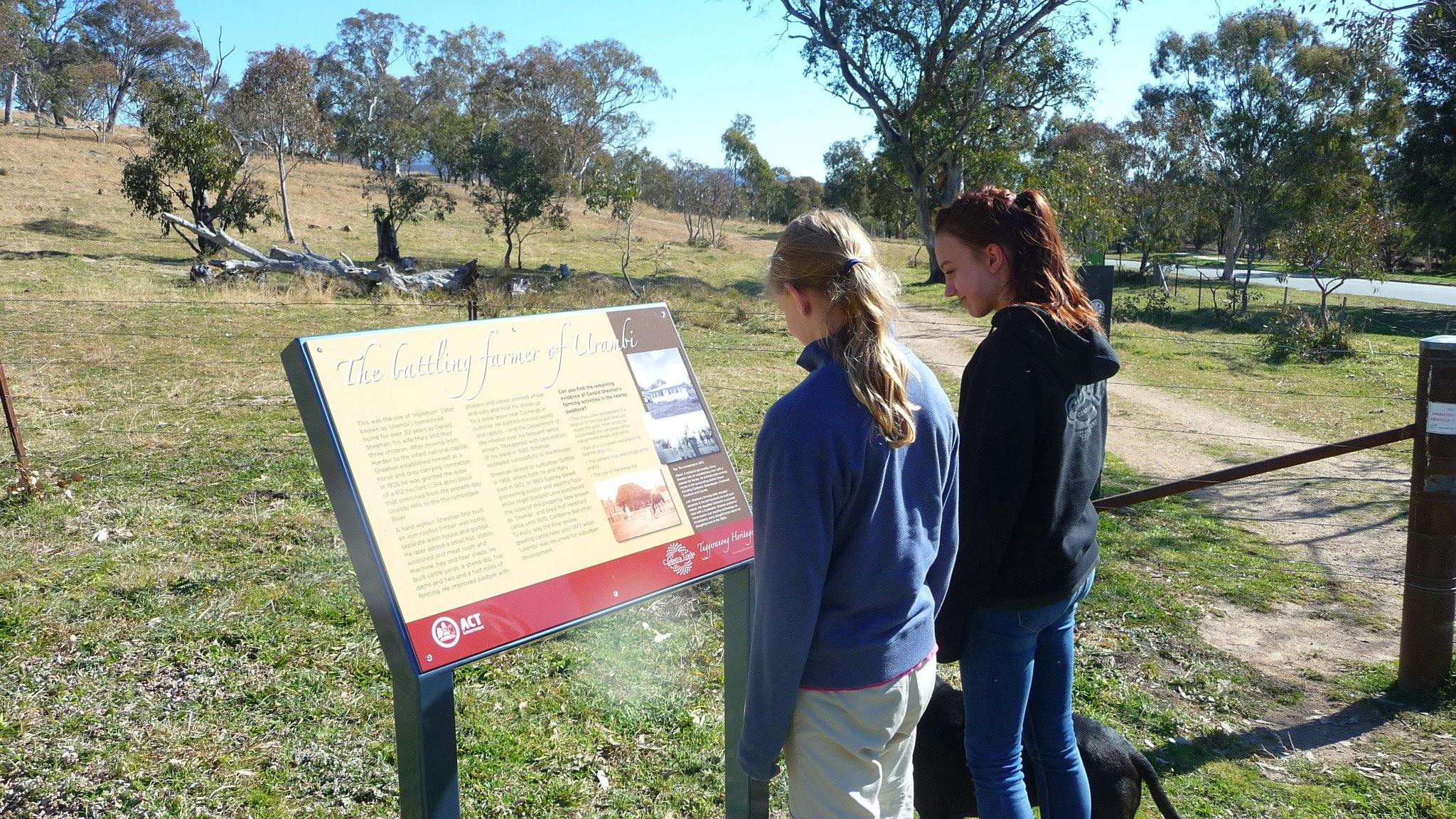 Two girls with dog at a sign board in open woodland