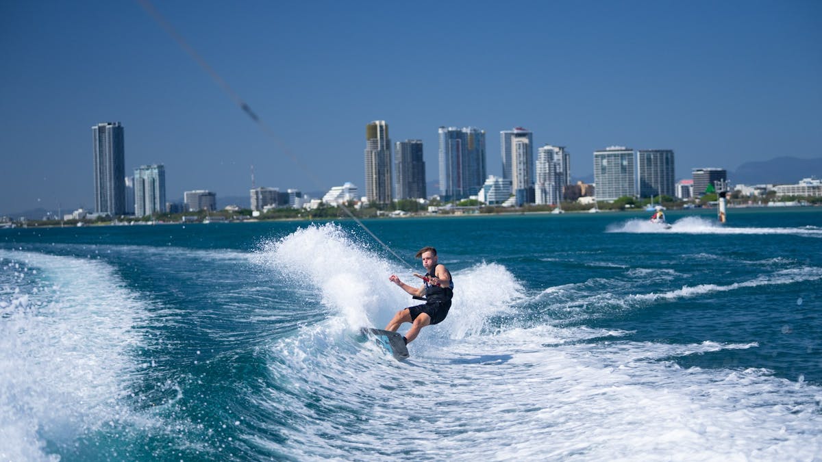 Wake boarder carving the wake with hise rise skyline in the background.