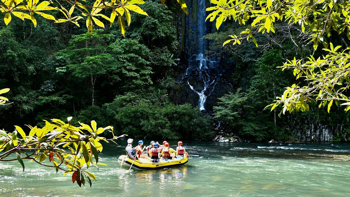 Wide shot of rafting boat in front of Champagne Falls waterfall on the Tully Gorge National Park