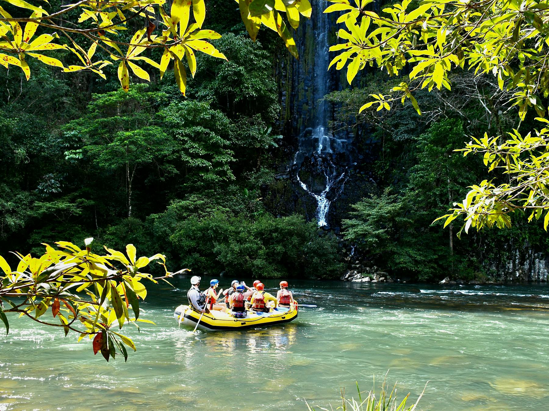 Wide shot of rafting boat in front of Champagne Falls waterfall on the Tully Gorge National Park