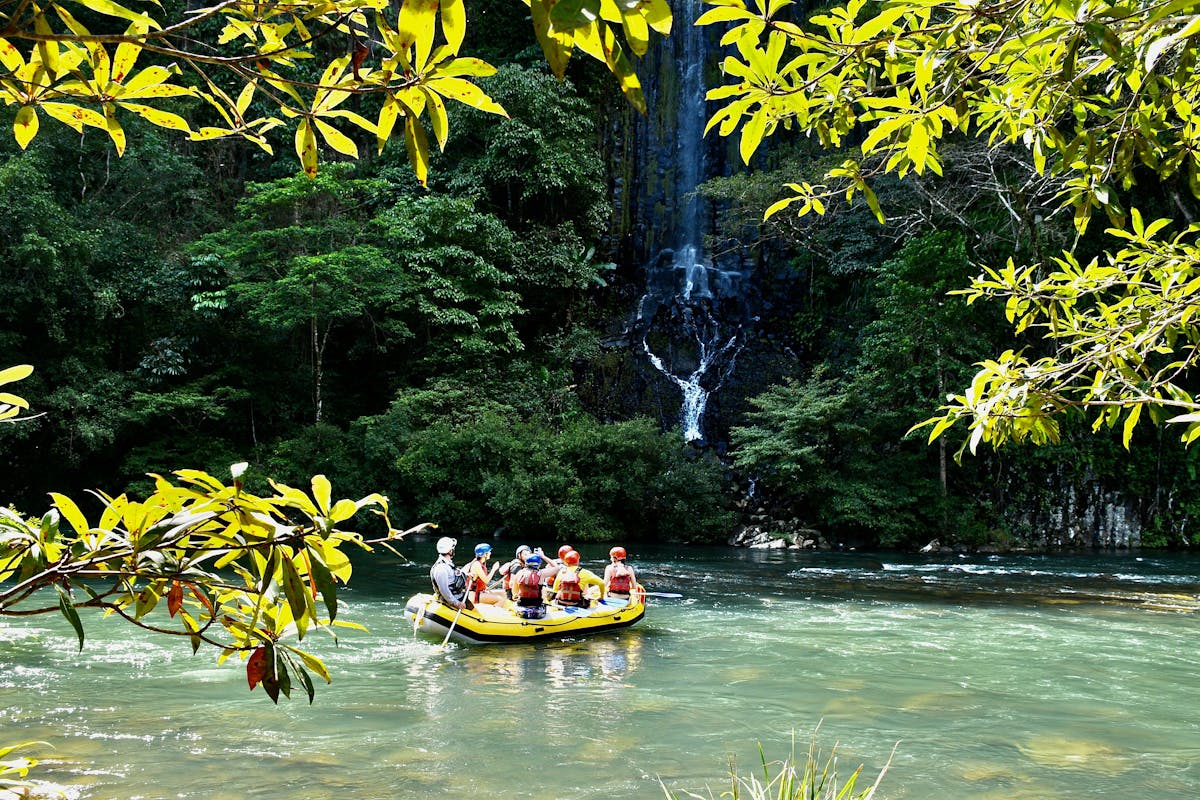 Wide shot of rafting boat in front of Champagne Falls waterfall on the Tully Gorge National Park