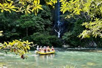 Wide shot of rafting boat in front of Champagne Falls waterfall on the Tully Gorge National Park