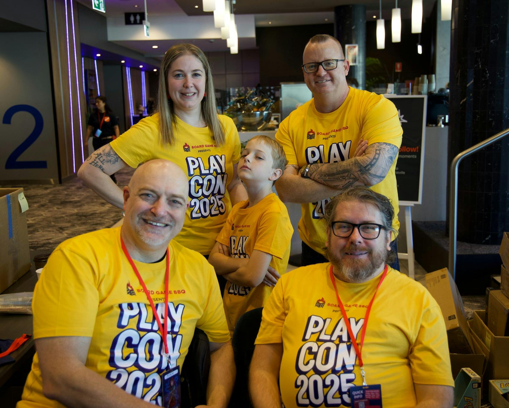 A group of volunteers in yellow shirts smile towards the camera at the check in desk at the event.