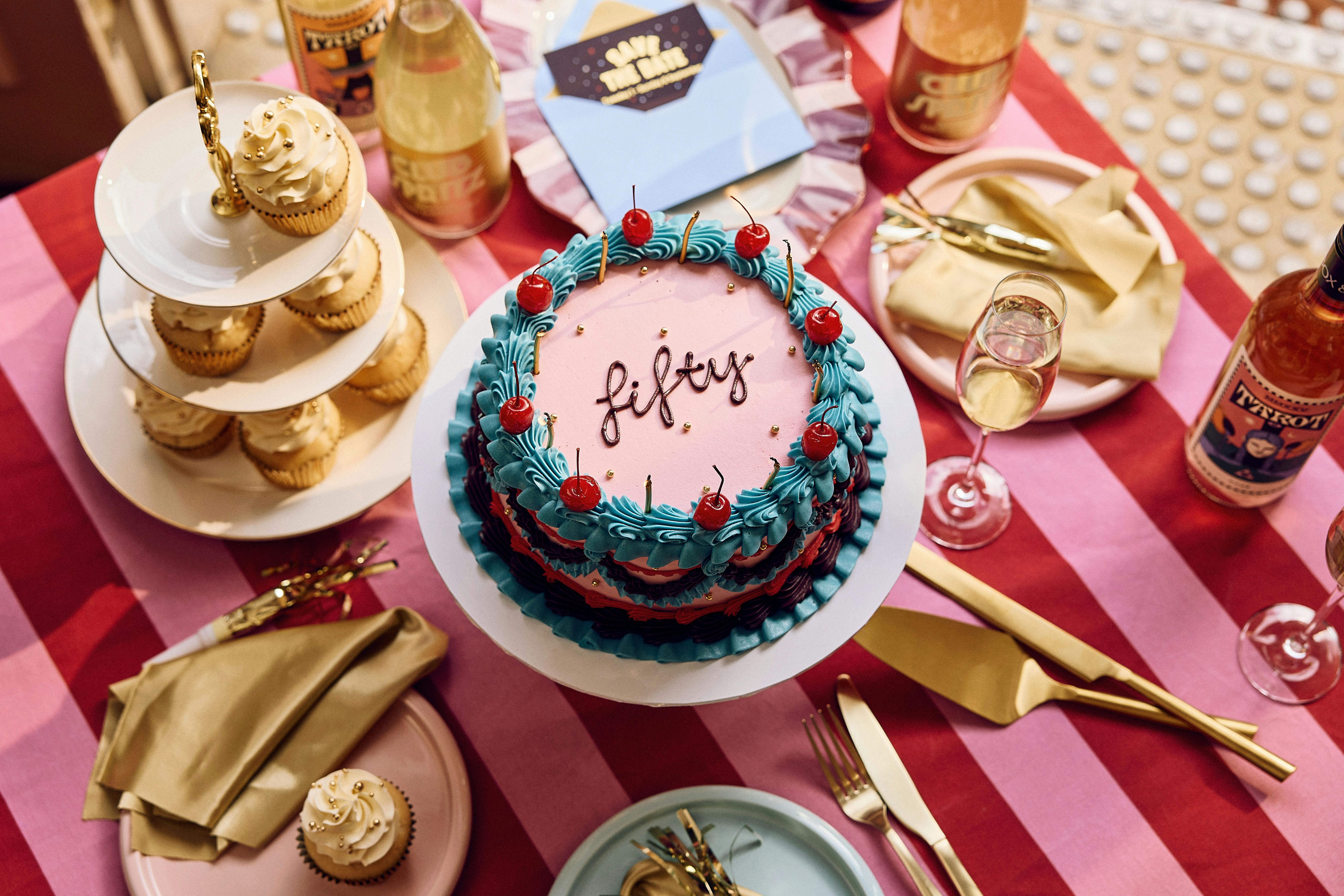 Brightly coloured table for a party and cake that says 'Fifty' on it