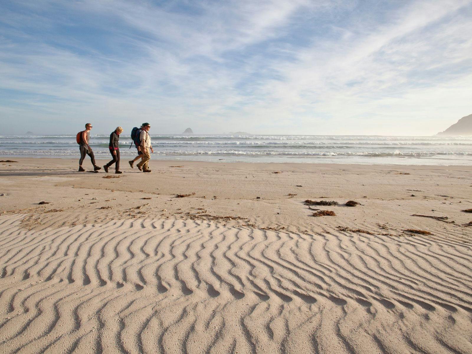 On Board's guests walk on a wild southern ocean beach in Port Davey, Southwest Tasmania