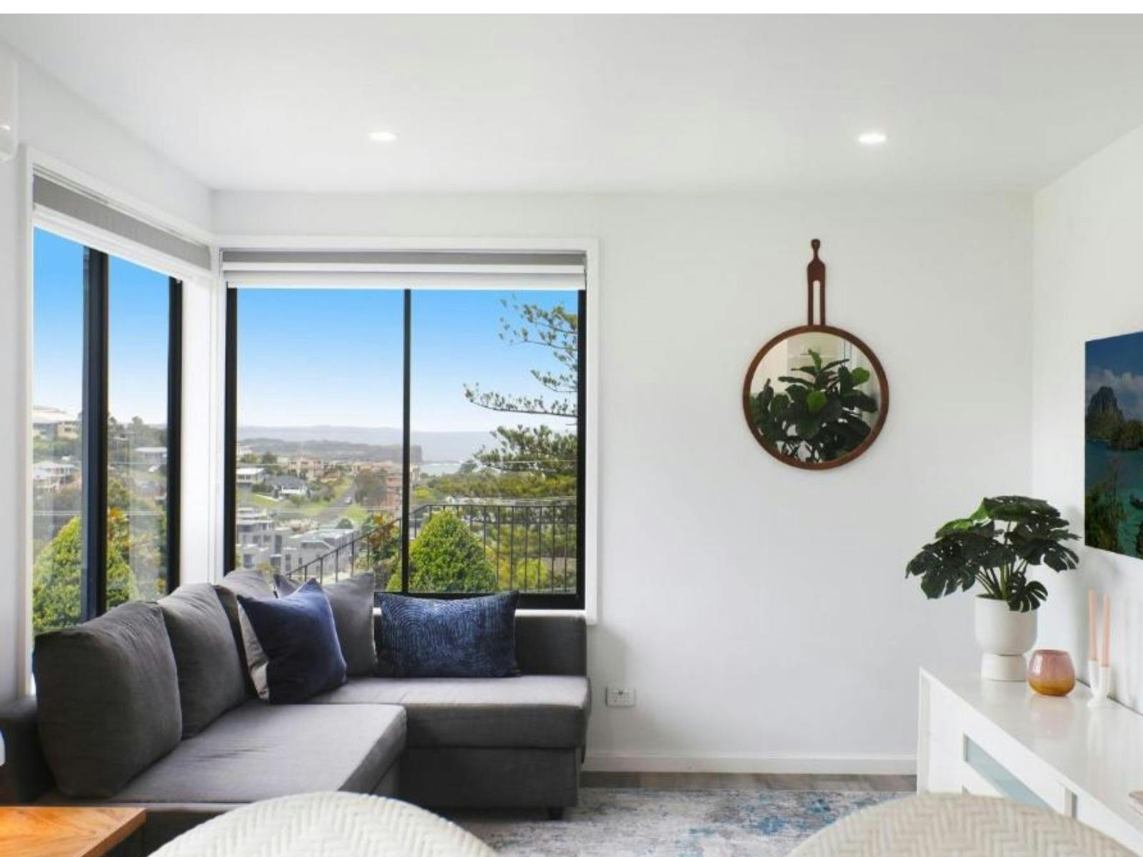 Loungeroom with corner couch, rug, tv and ocean views in background
