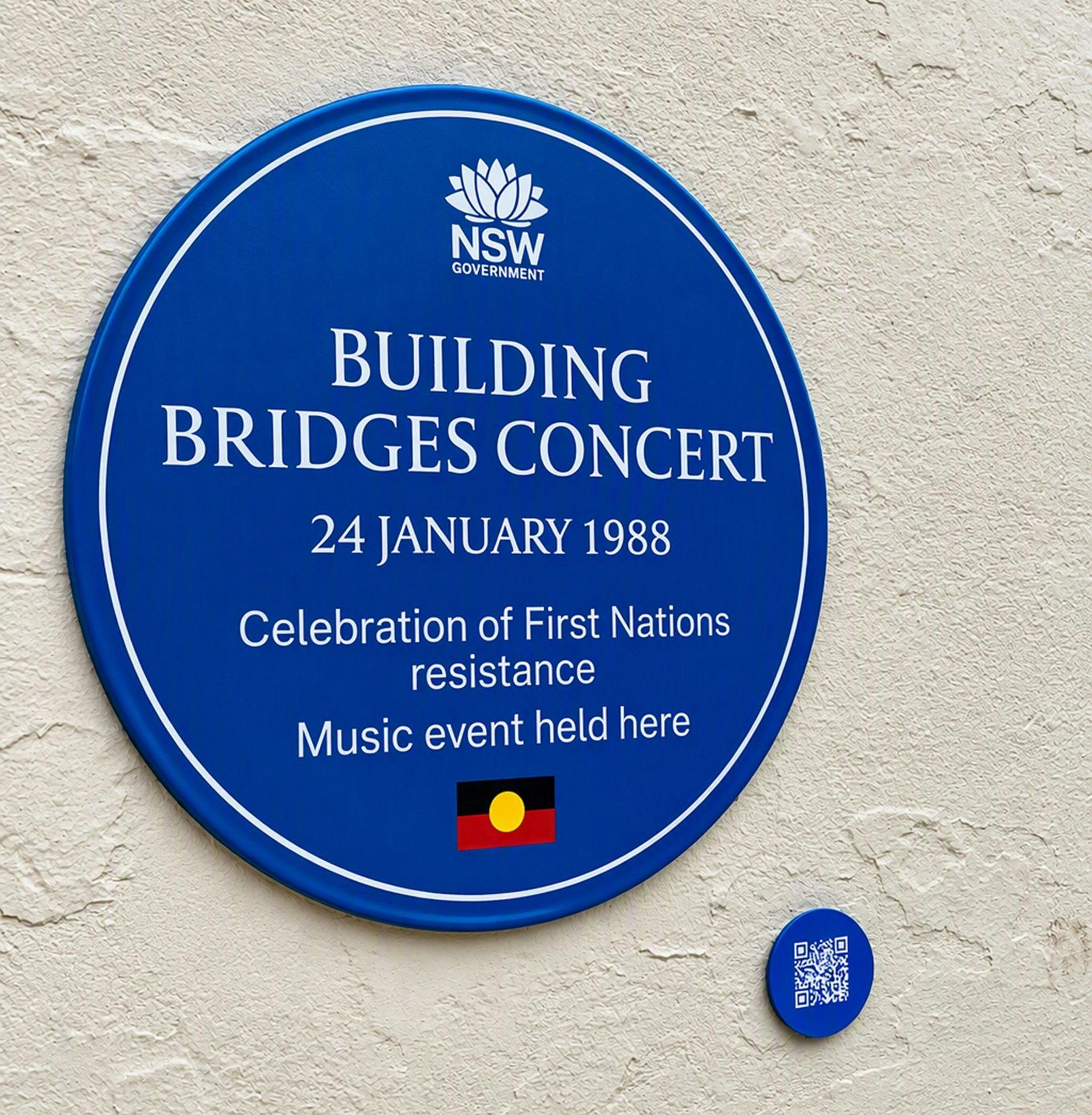 Blue plaque with Aboriginal flag on cream coloured rendered concrete wall