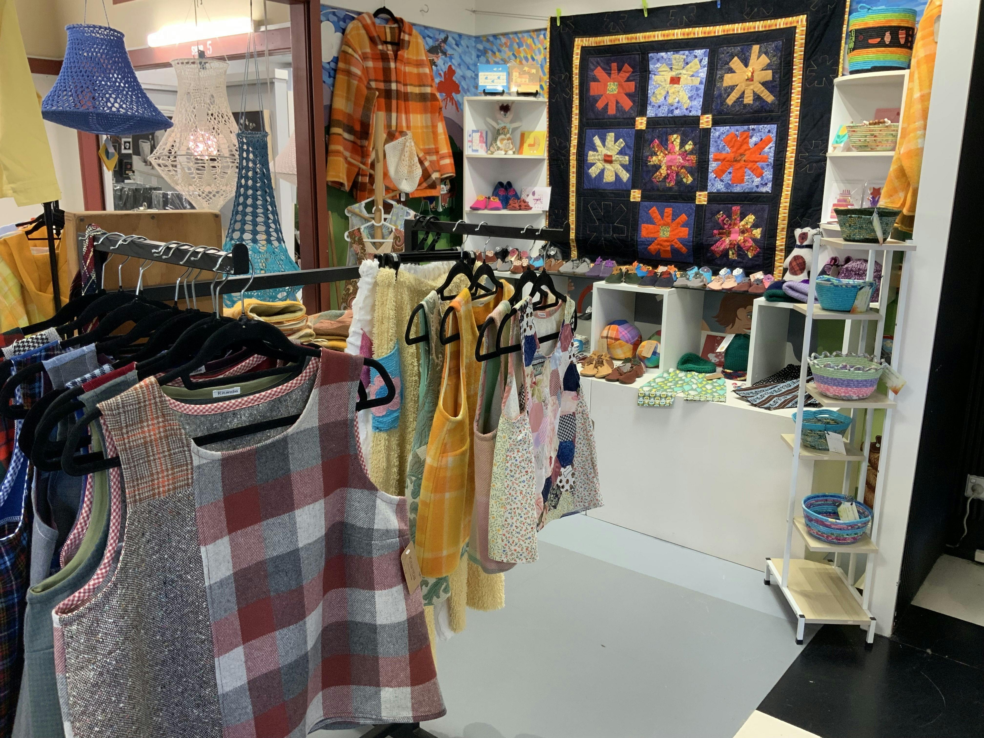 Photo of inside the gallery showing Woollen vests and a quilt in the background