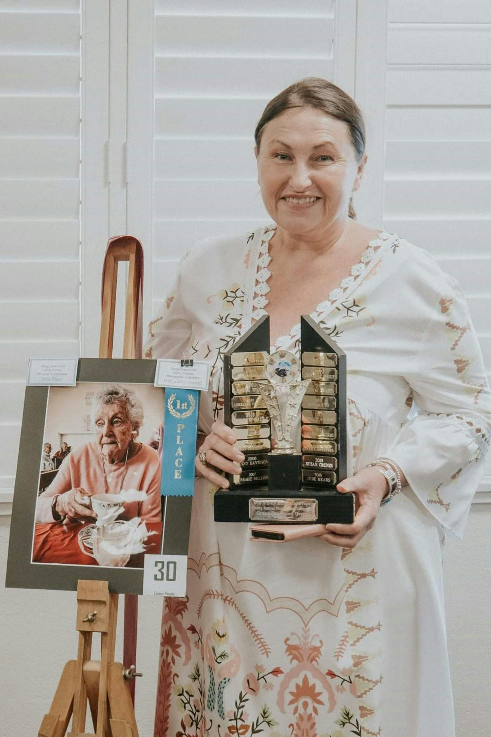 Tammy McGaw Mary's photograph winning first place and a trohpy being held.