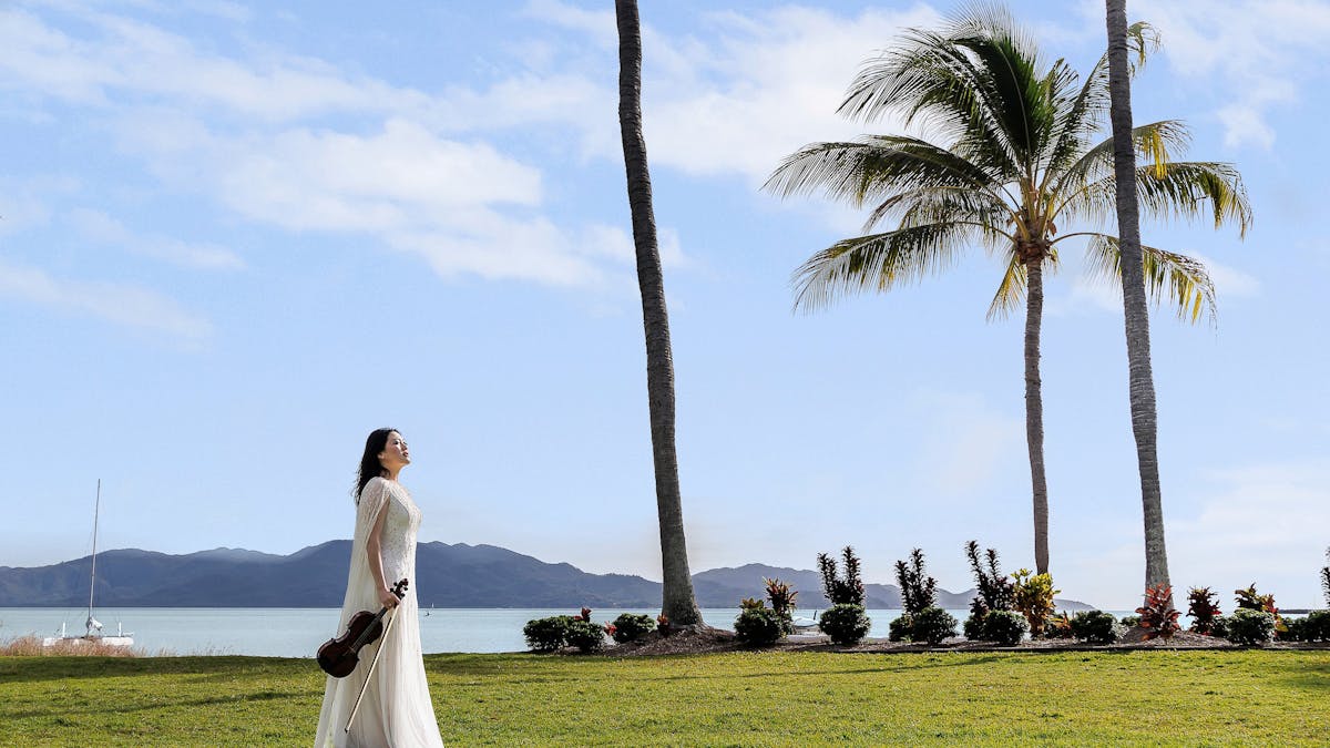 AFCM Promo image_Musician on grass in front of beach in Townsville