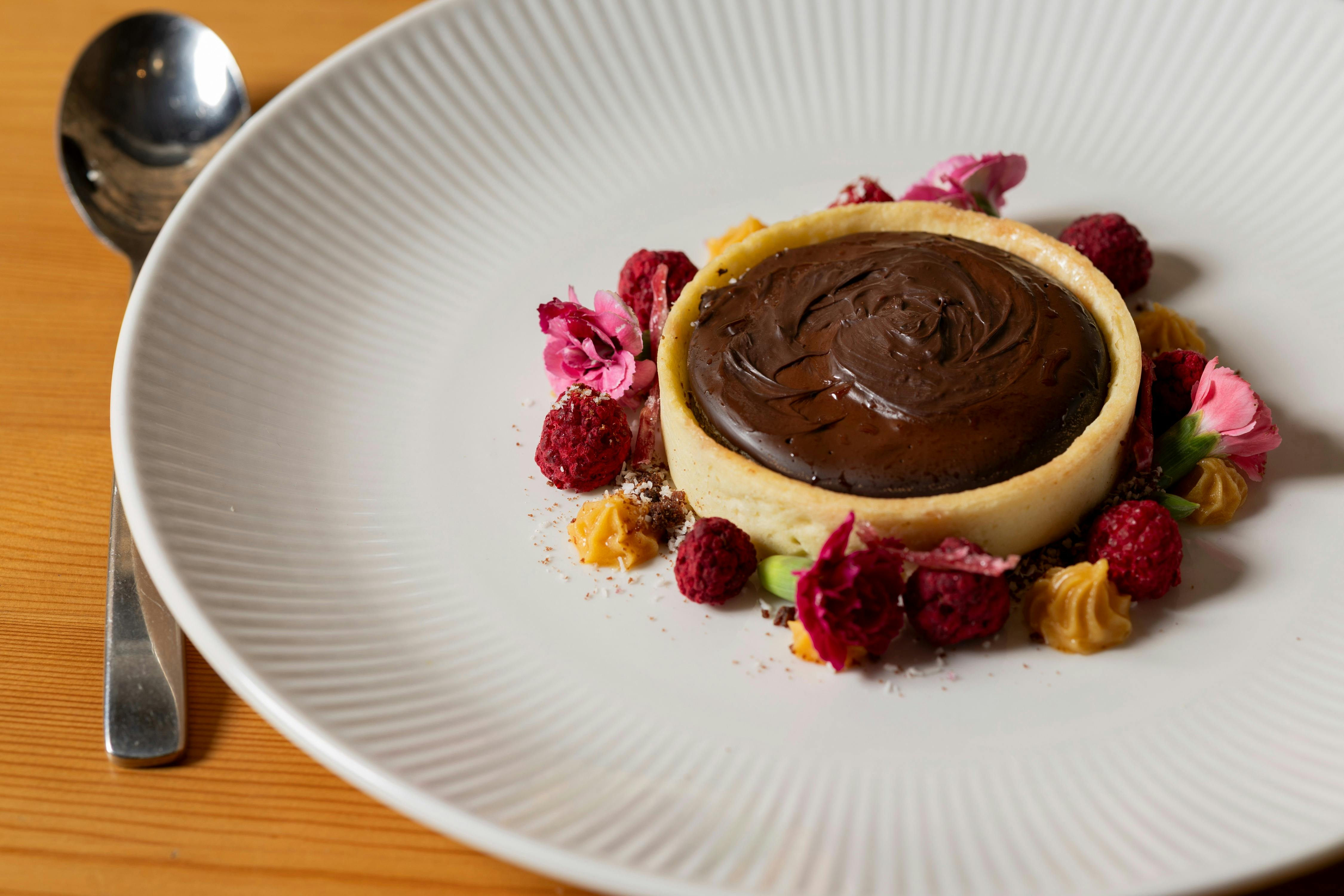 Chocolate tart with pink and red flowers around the circle
