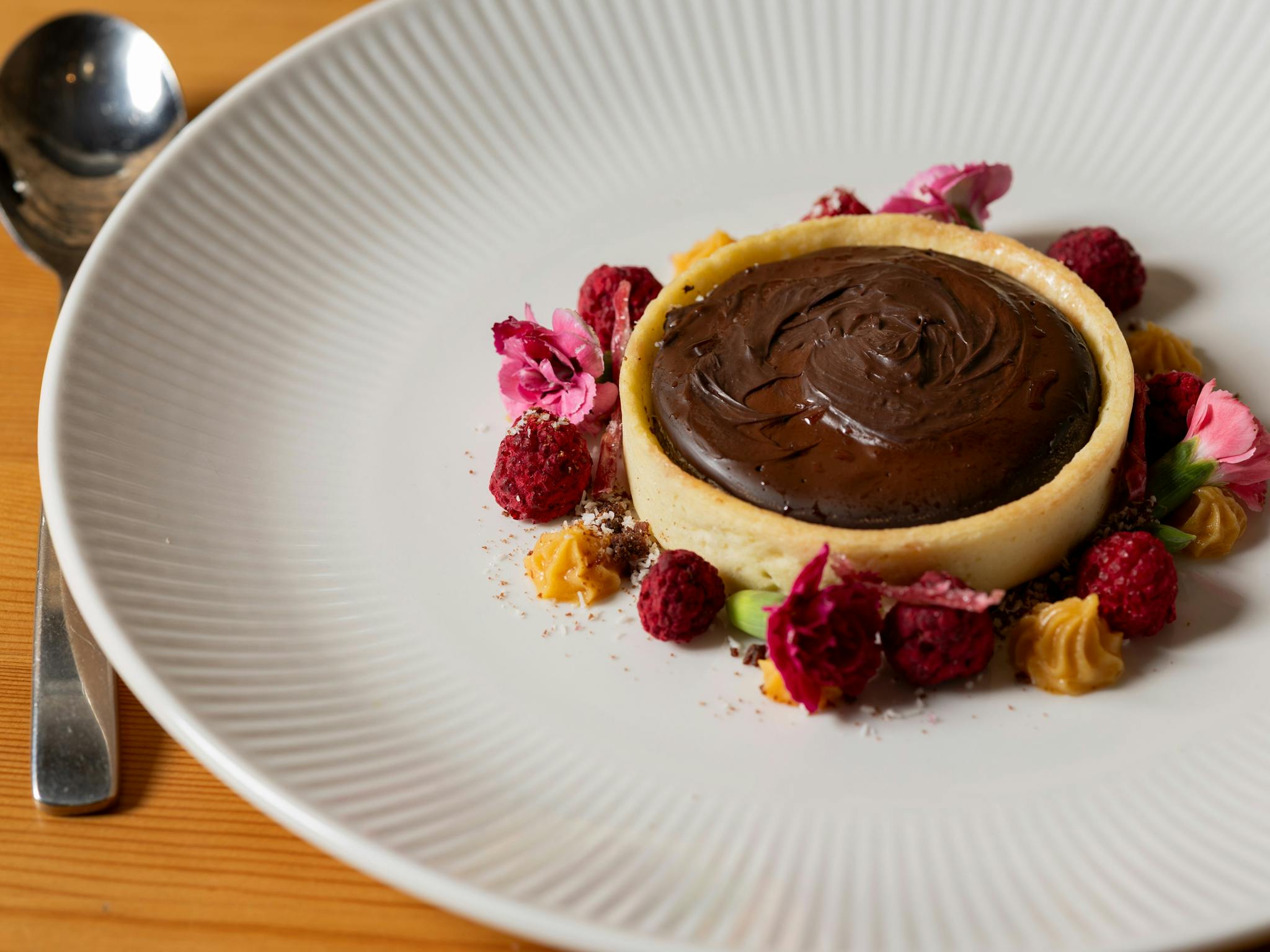 Chocolate tart with pink and red flowers around the circle