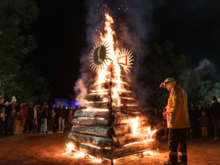 A firefighter lights up a wooden tower with flames