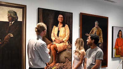 People facing portraits on a wall