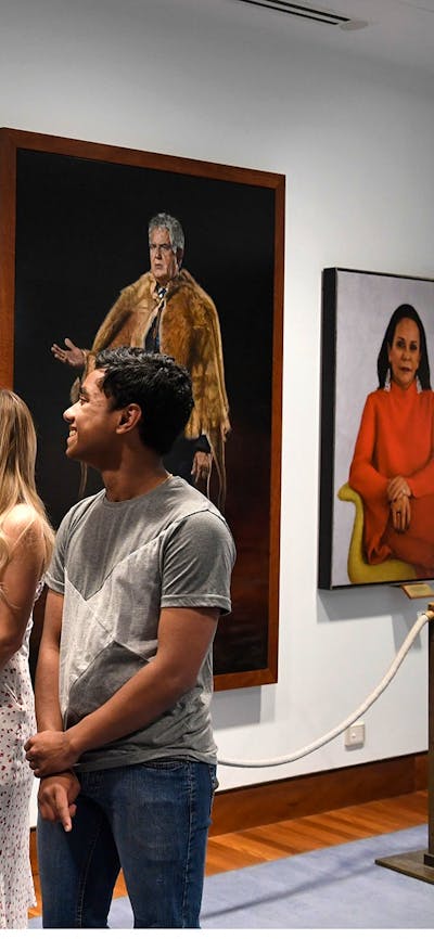 People facing portraits on a wall