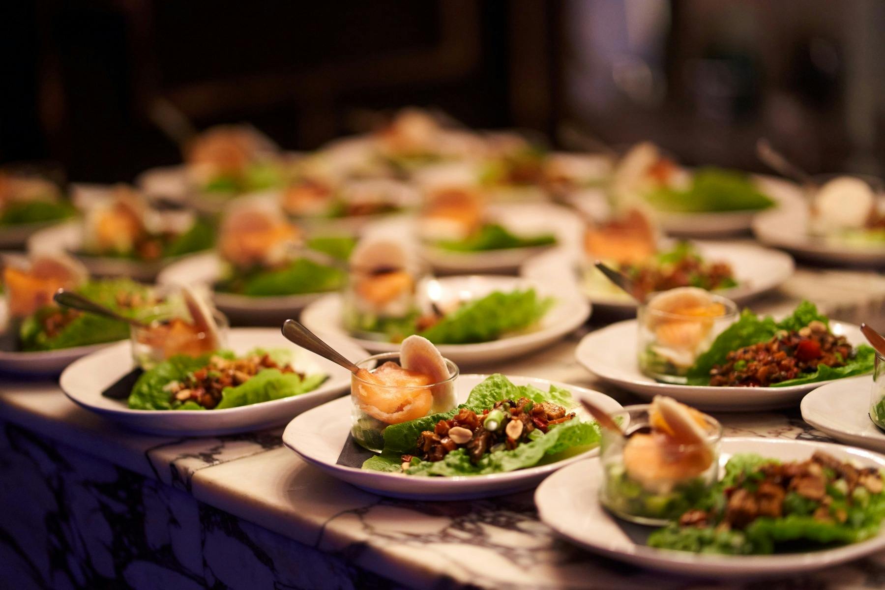 Rows of fresh salmon entrees on small plates ready to be served from the marble bar top