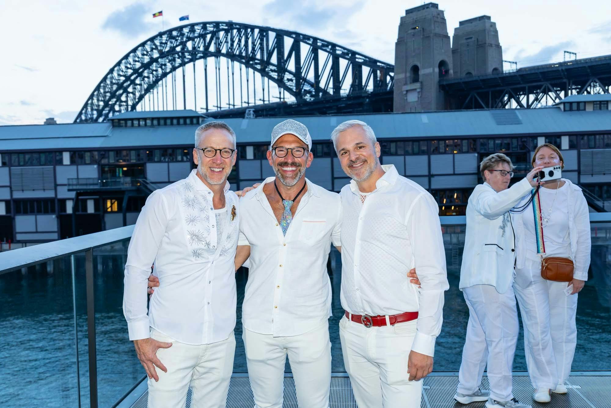 Three guests in white posing by Sydney Harbour Bridge.