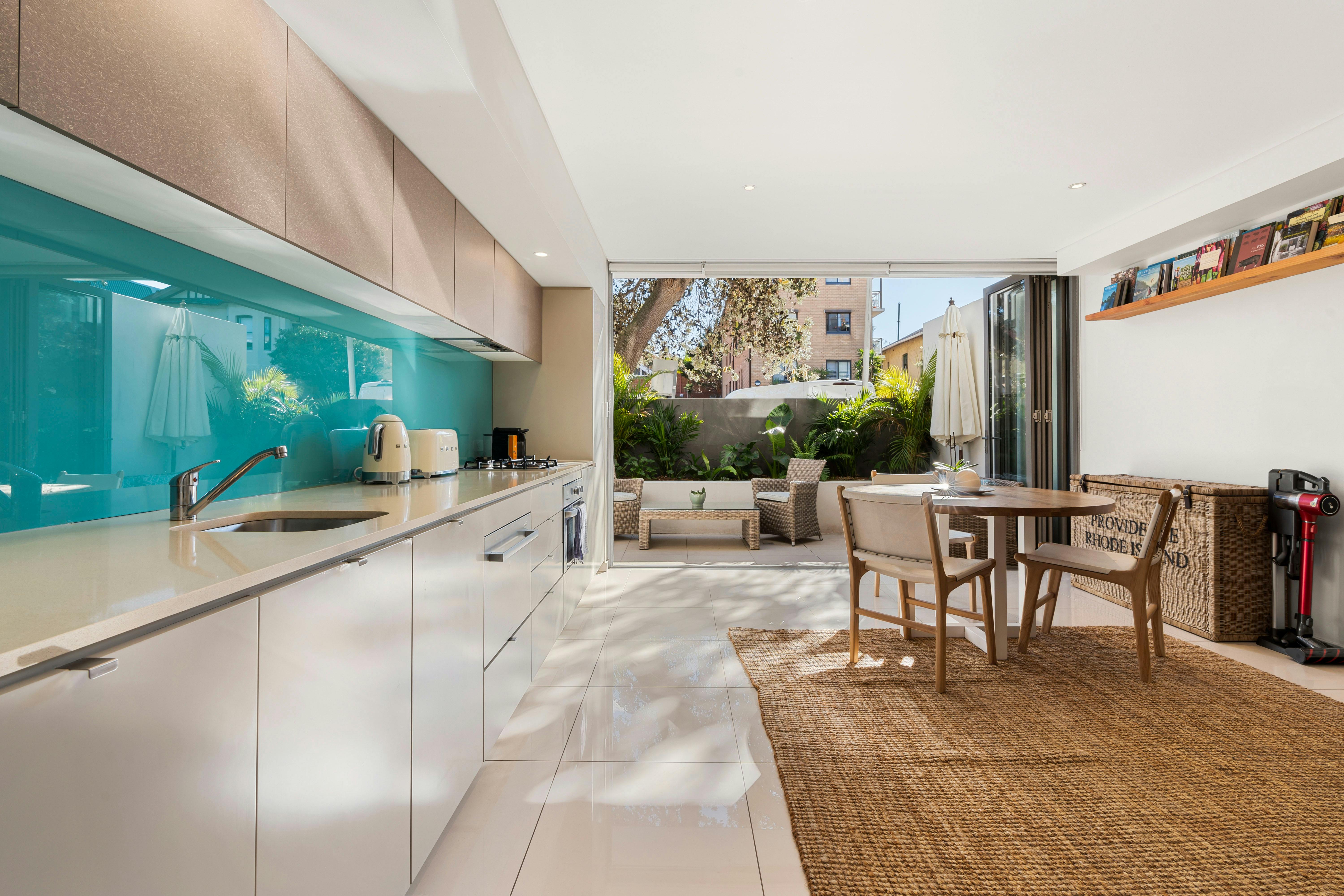 Modern kitchen and living space with a turquoise splashback and a cozy private courtyard.