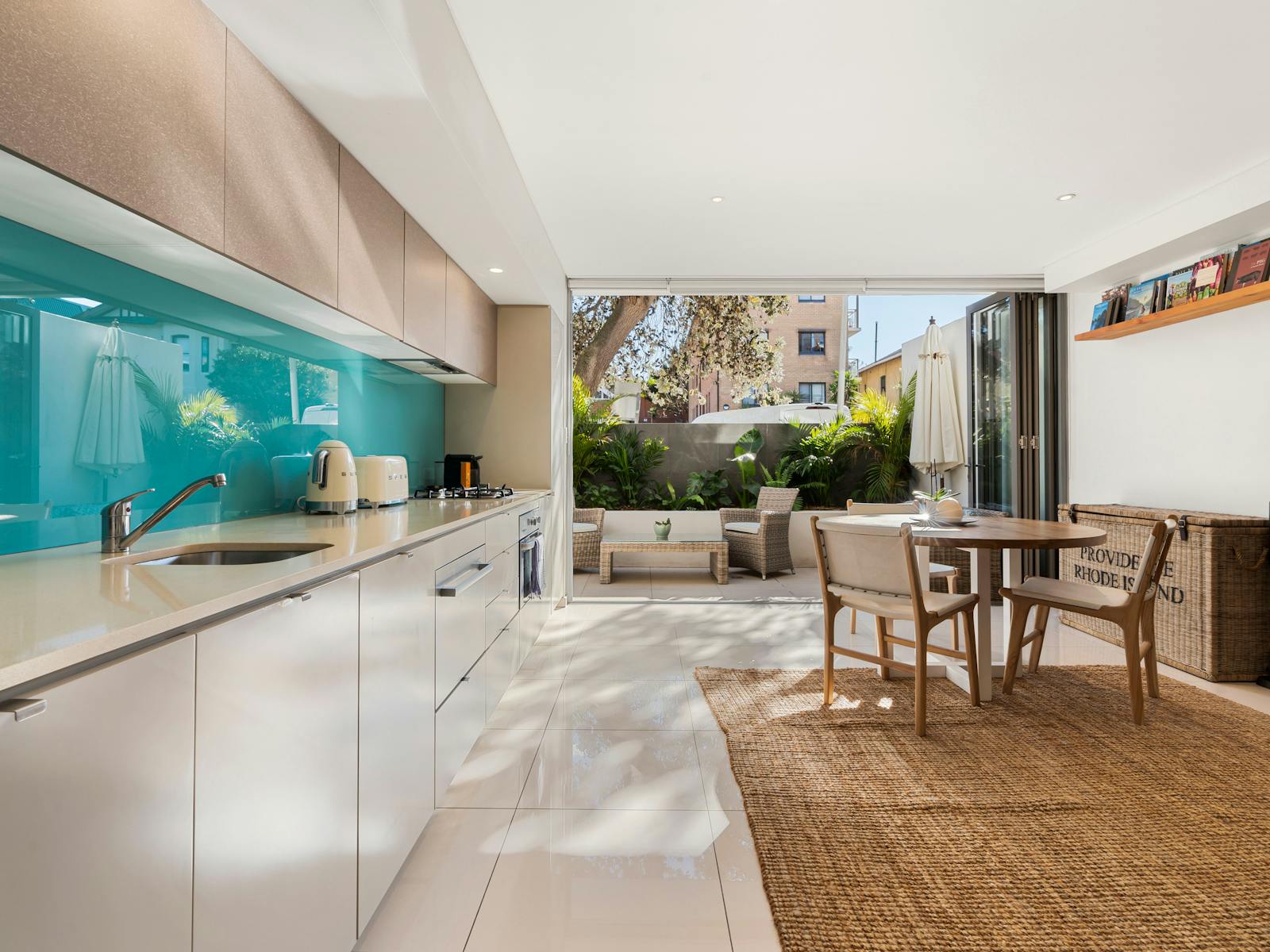 Modern kitchen and living space with a turquoise splashback and a cozy private courtyard.