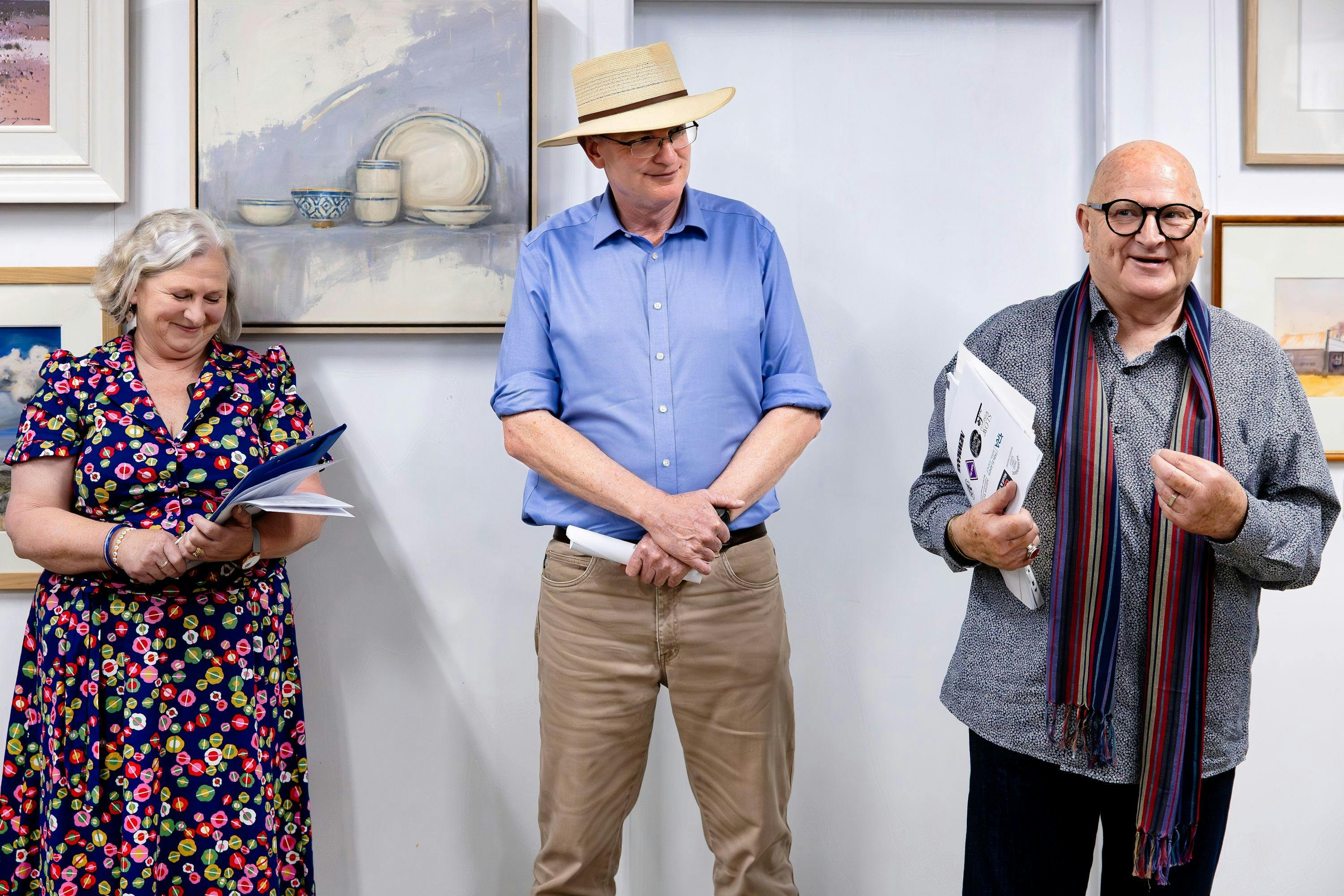 右側では、灰色のシャツを着て長い色のスカーフを巻いた男性が話しています。