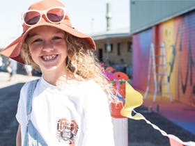 Curly haired girl in front of George Rose Mural 2018