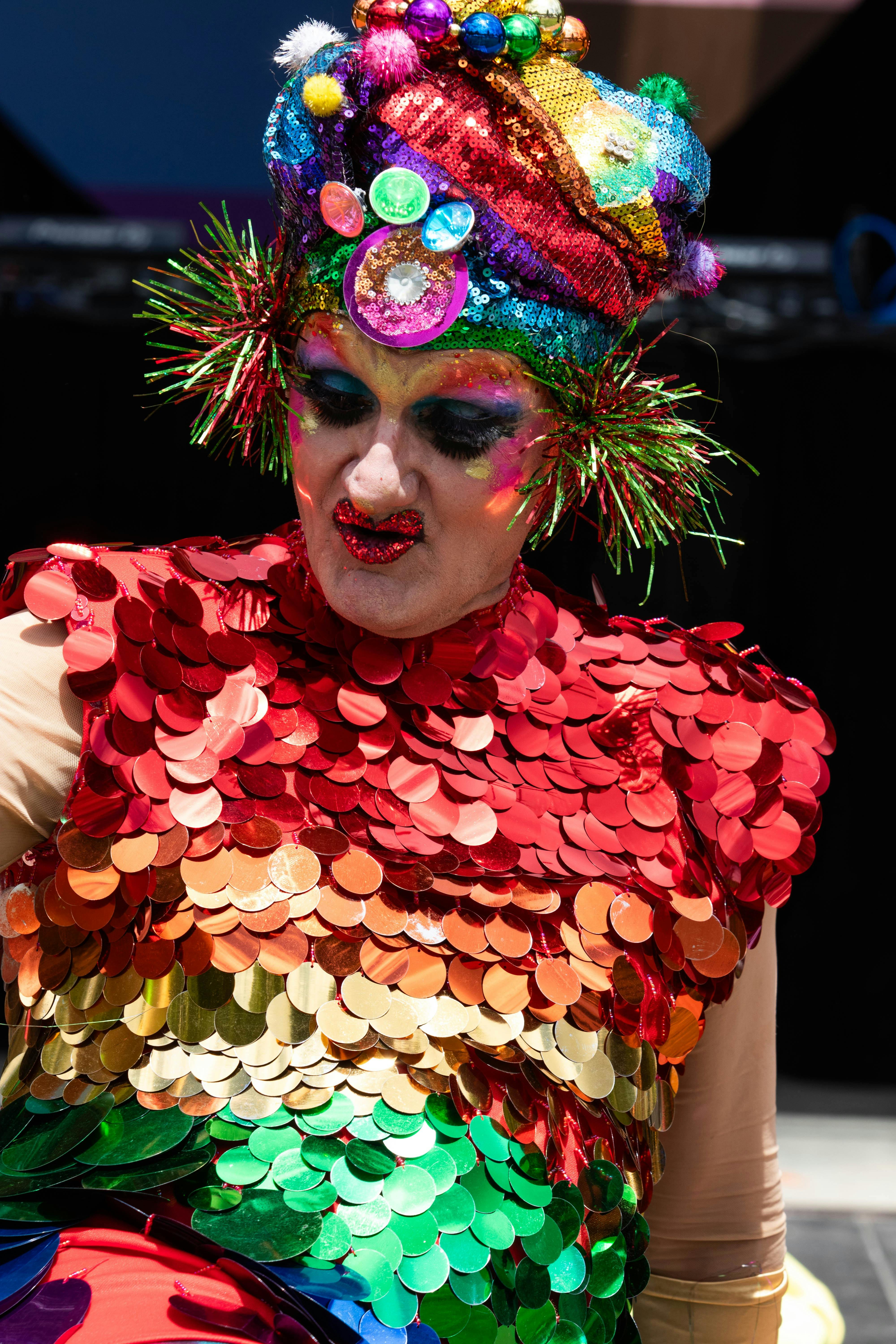 Drag Performer in brightly coloured costume and headress performing at Fair Day