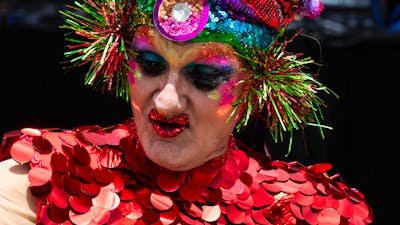 Drag Performer in brightly coloured costume and headress performing at Fair Day