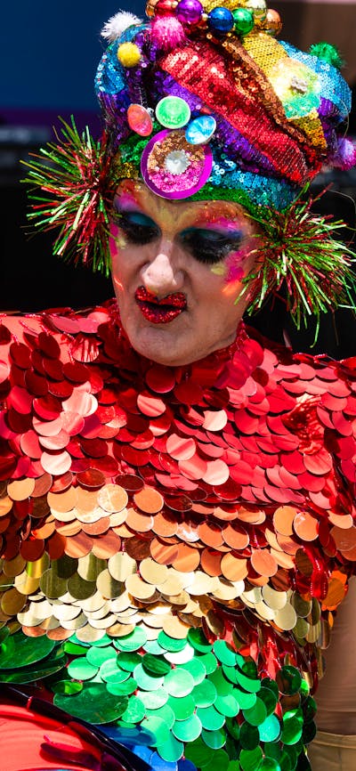 Drag Performer in brightly coloured costume and headress performing at Fair Day
