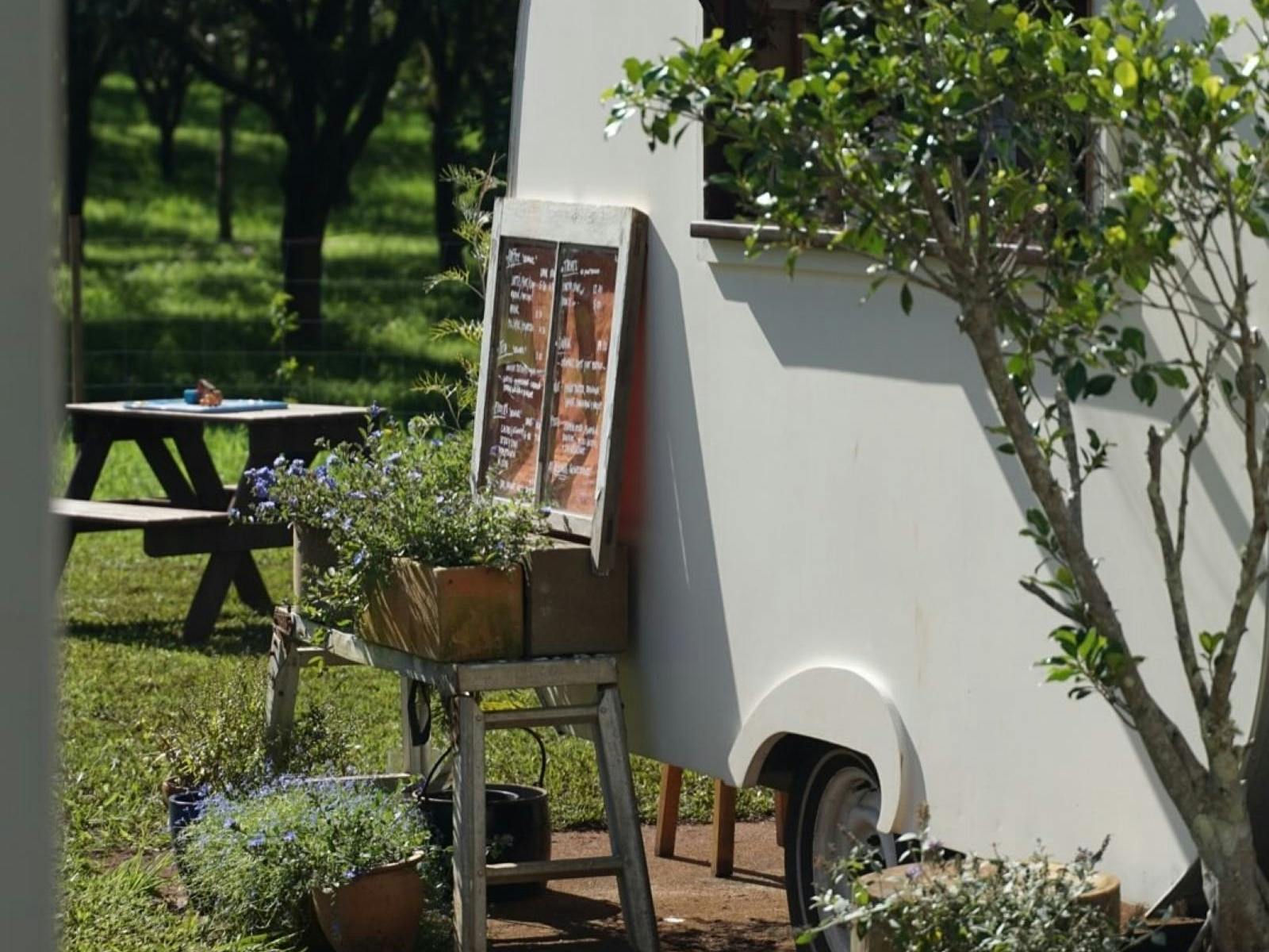 little white caravan with small timber deck in green field with picnic table