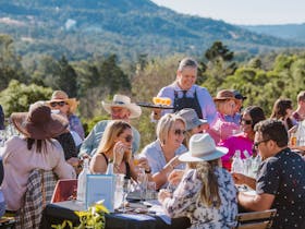 A group of people enjoying a four-course meal at My Country Escape, surrounded by rolling hills.