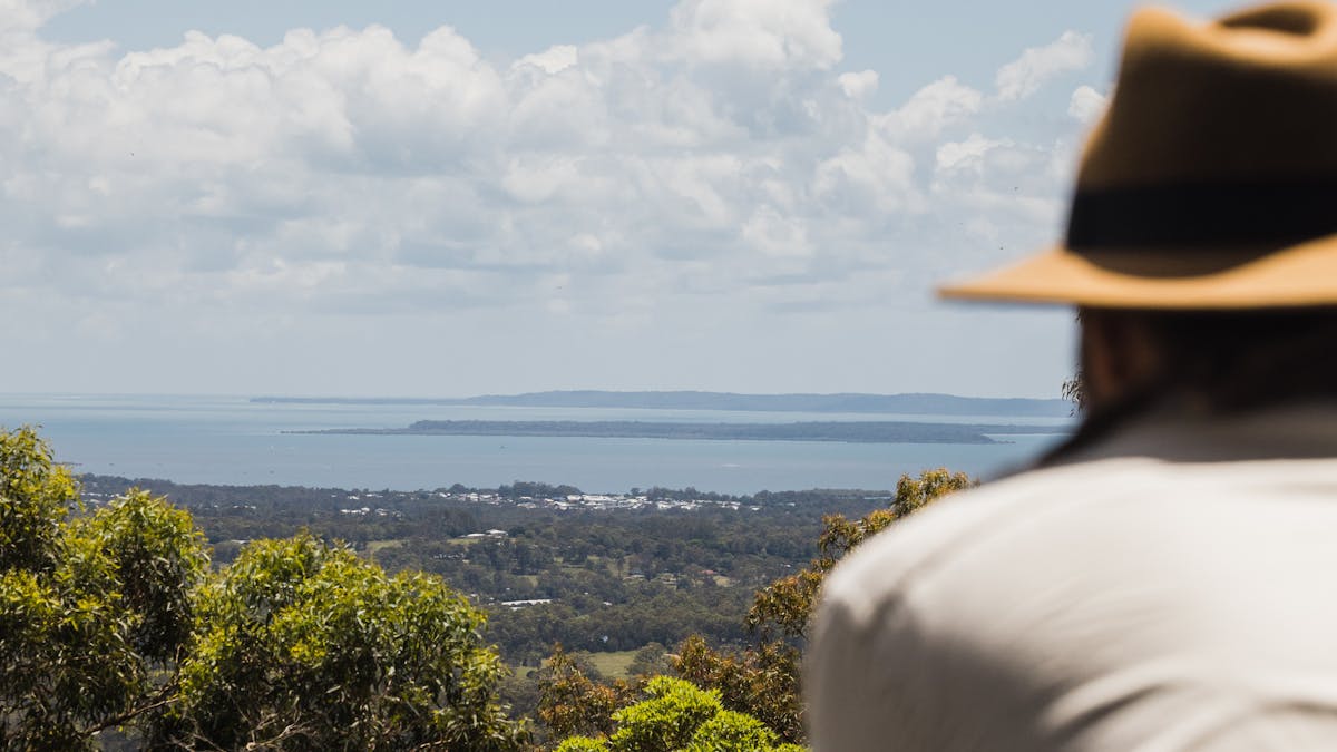Person admiring panoramic views of Minjerribah from the Eastern Escarpment Conservation Area
