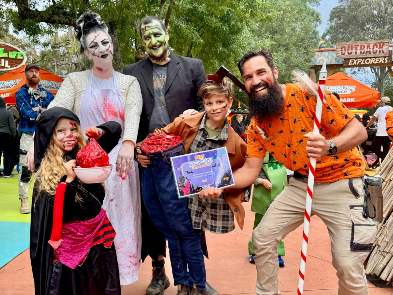 Halloween costumed guests and Gumbuya World team member pose together during a spooky family event.